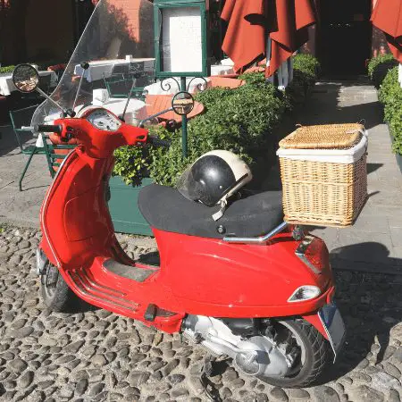 Red scooter with a wicker basket on the back rack