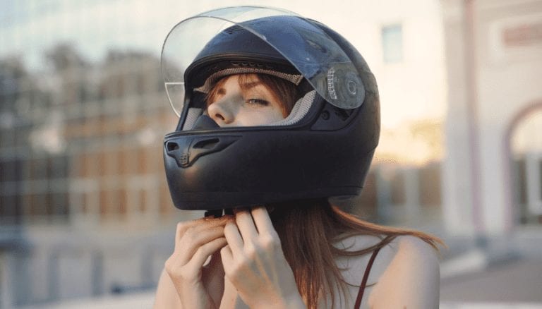Woman with long hair putting on motorcycle helmet