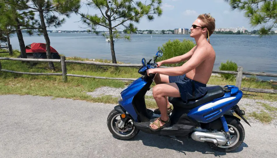 Man riding a scooter on vacation near a lake