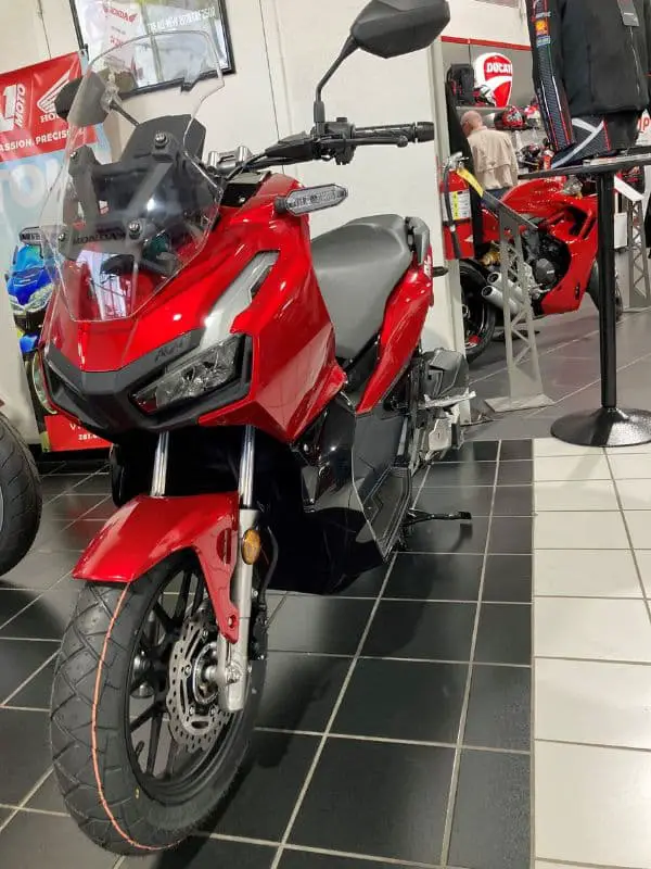 Front profile of a red Honda ADV scooter at a dealership