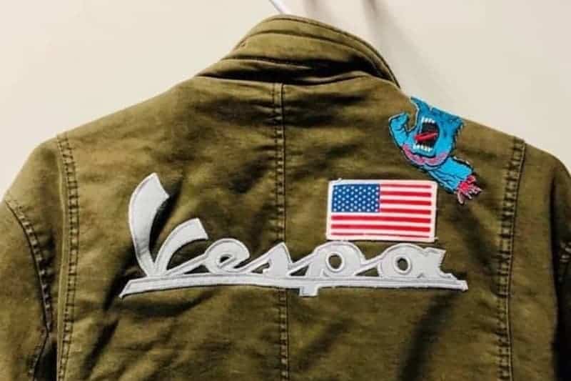 silver reflective Vespa patch on a green jacket