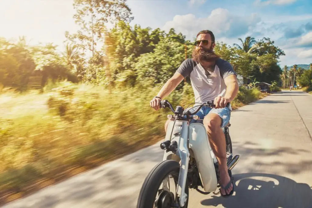 man not wearing a helmet, pants, sleeves or any protective gear riding with a blur of a background visible