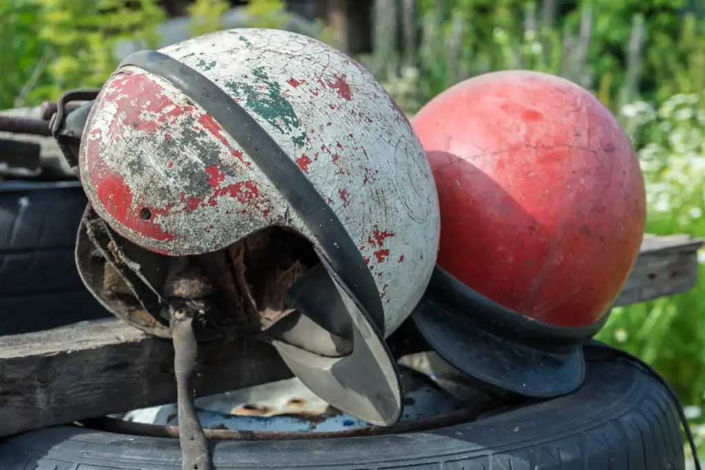 2 helmets with visible damange - cracked, peeling exteriors, worn & harden straps and interior liners