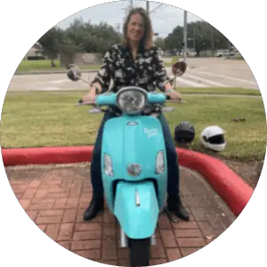 Renee, Scooter Newbie sitting on the 2020 Buddy Kick in a parking lot