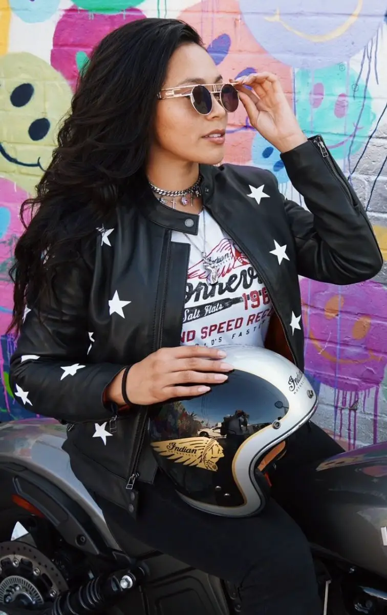 Woman rider in a black leather jacket from Wind & Throttle. It has reflective white stars on it.