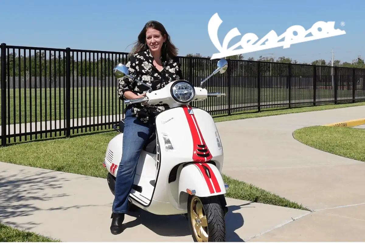 woman sitting on a white vespa with a red stripe