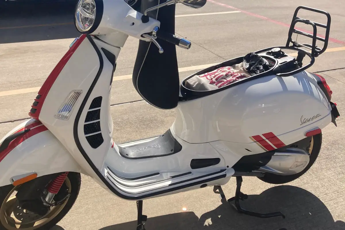 Vespa GTS with a bag and motorcycle gloves in the storage box.