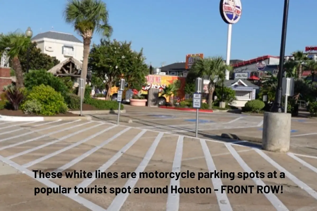 painted white lines and signage that indicates motorcycle specific parking just beyond handicap parking at a tourist spot that gets crowded