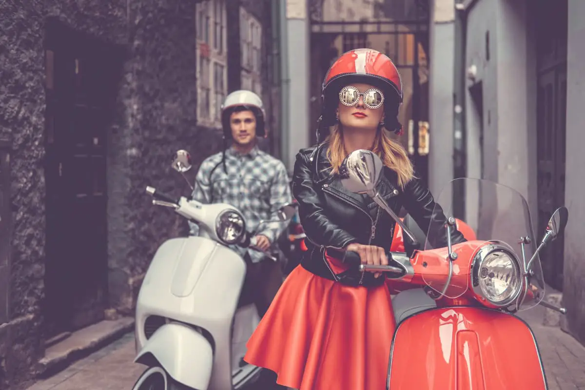 couple gearing up to ride on Vespa
