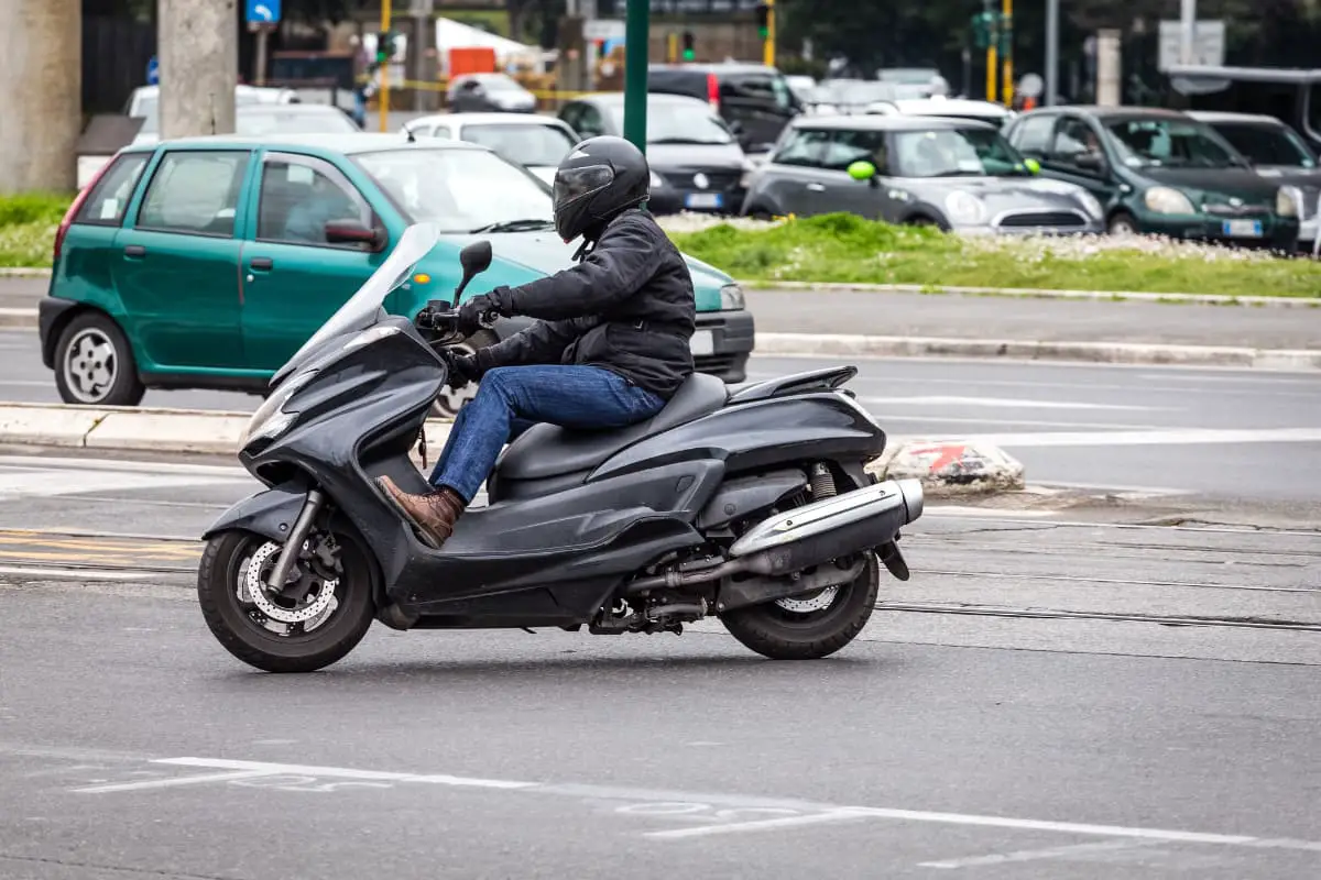 Scooterist riding a maxi scooter in full gear in a more relaxed position instead of on the bottom floor space.