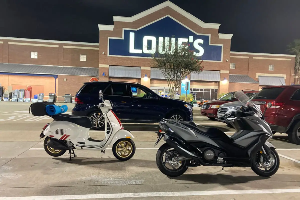 White Vespa GTS 300 Racing Sixties sharing a parking space with a matte silver Kymco AK550