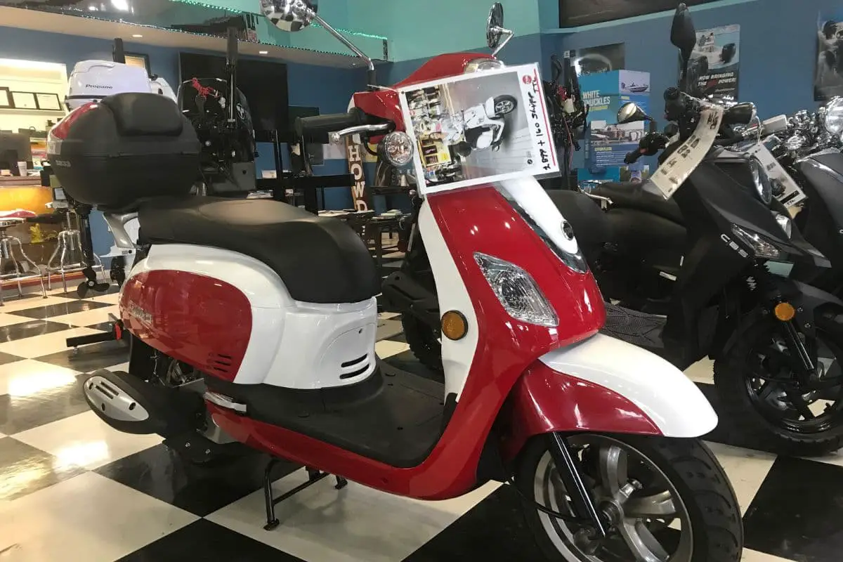 red and white sym fiddle iii at a scooter dealership