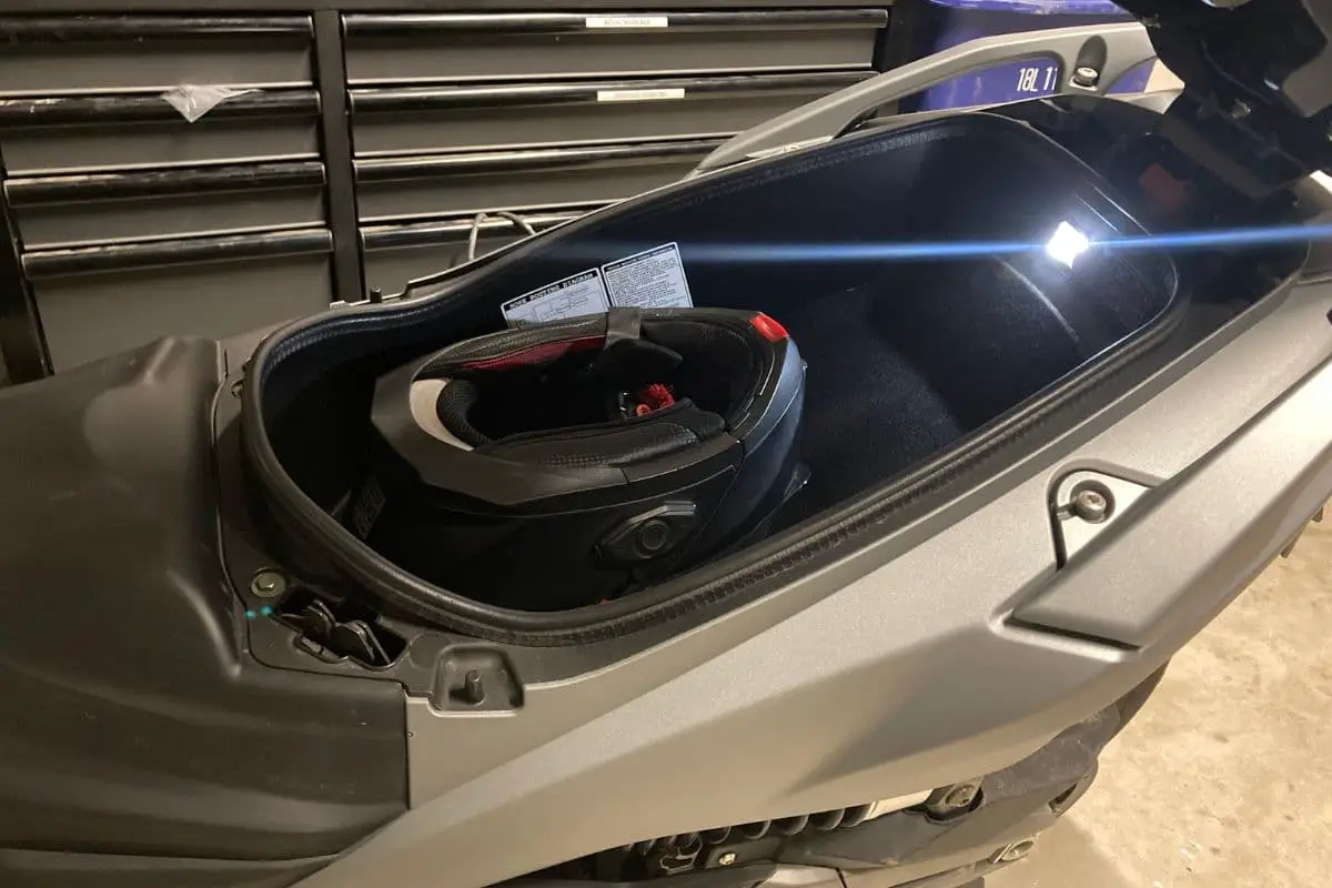 full face helmet upside down in the underseat storage compartment with an LED light