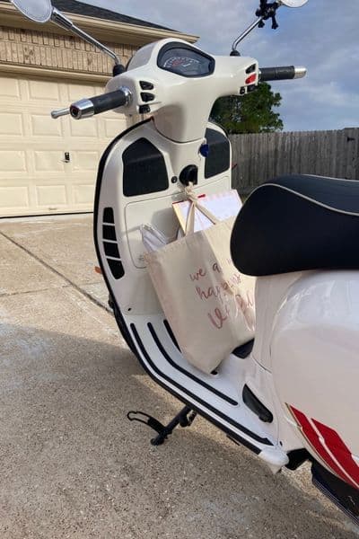 Full shopping bag hanging on hook of a Vespa leg shield